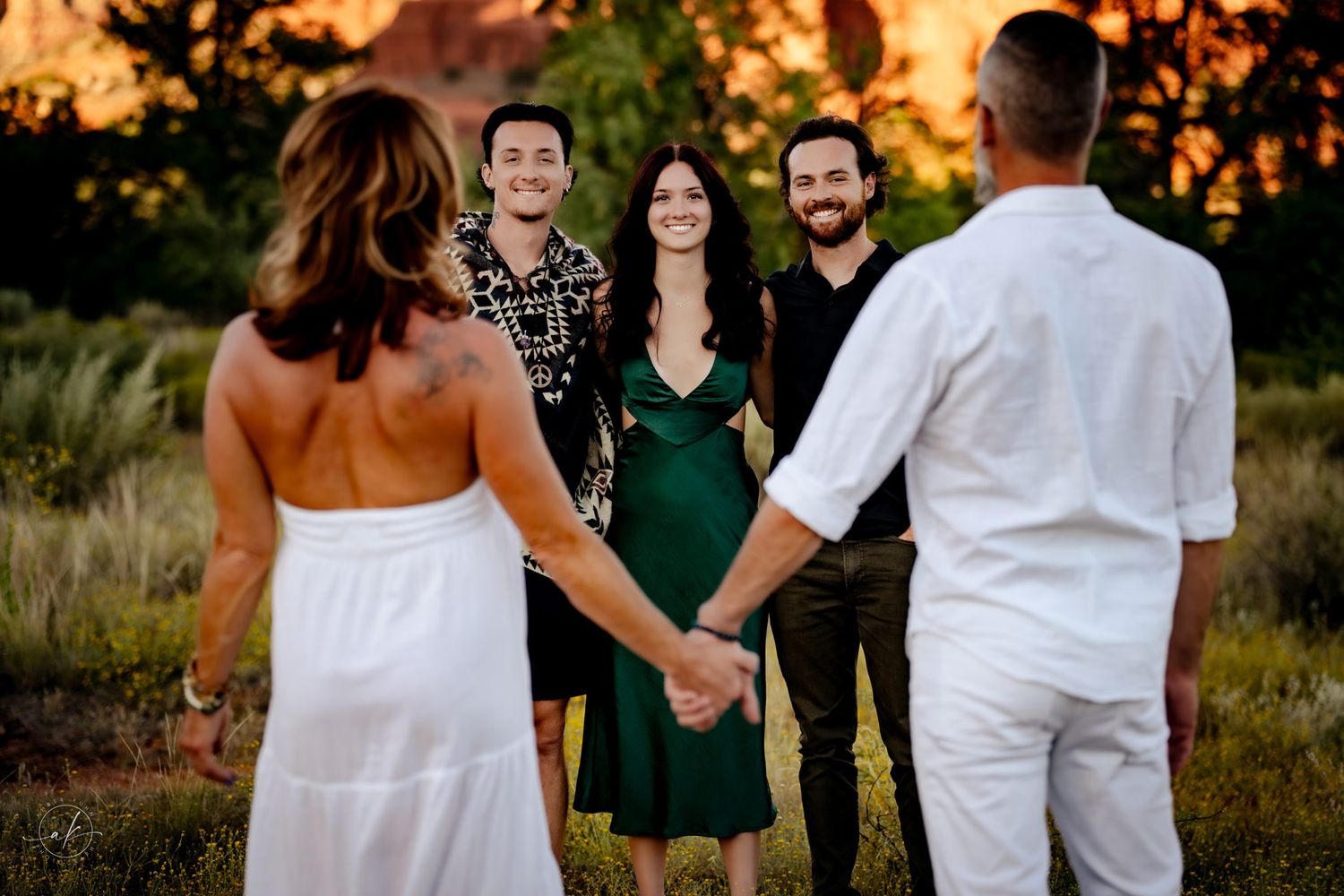 A group gathers for an intimate outdoor ceremony against a Sedona sunset backdrop.