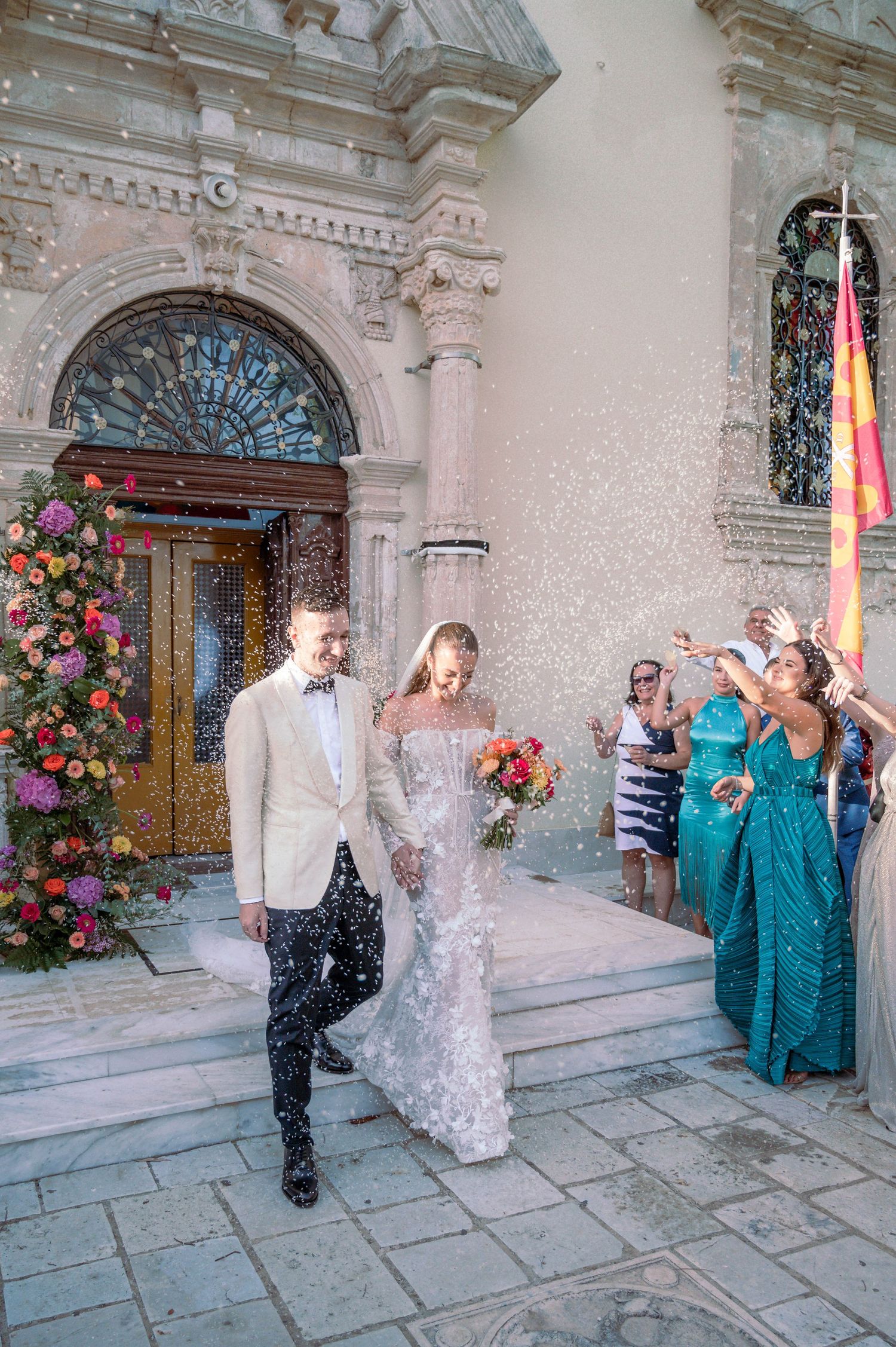 Bride and groom exiting church during wedding celebration with guests throwing confetti.