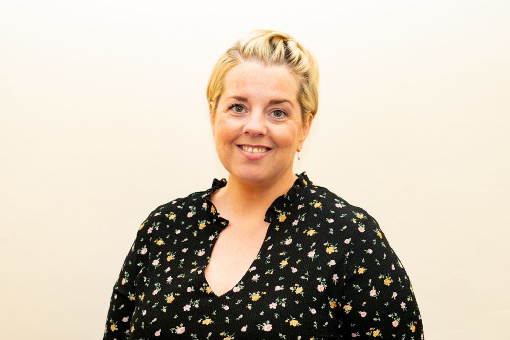Person in black floral dress stands against white background in three similar poses.