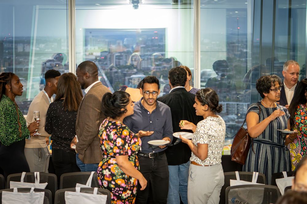 Couples dancing together in an indoor venue with large windows overlooking city views during a social gathering.