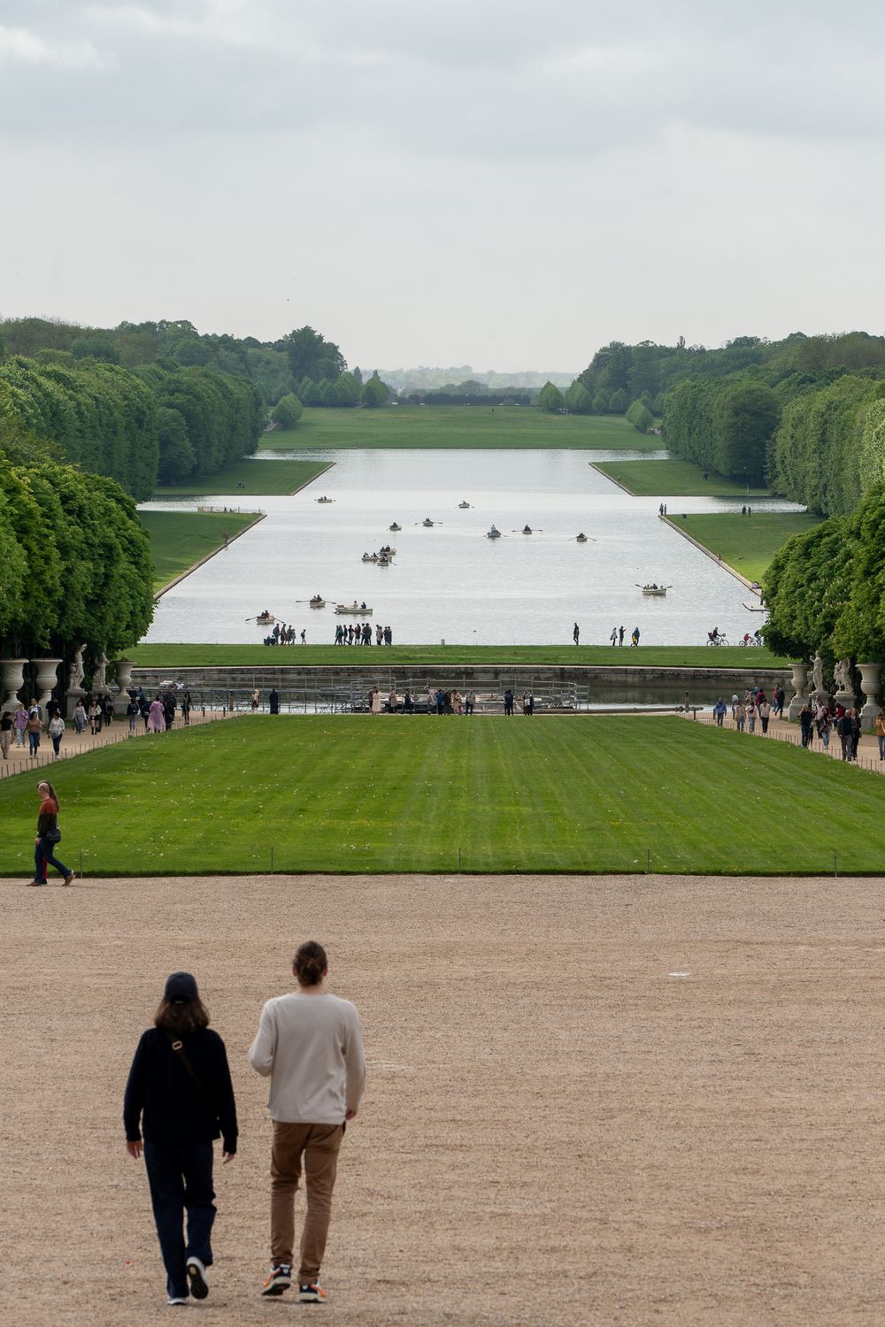 Grand perspective of Palace of Versailles gardens with large reflecting pool and manicured trees.