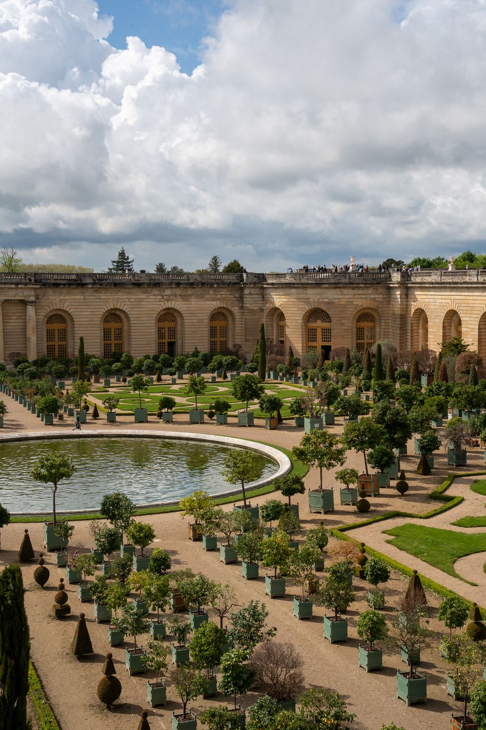 Ornate palace gardens with circular pool and symmetrical landscaping at Versailles.