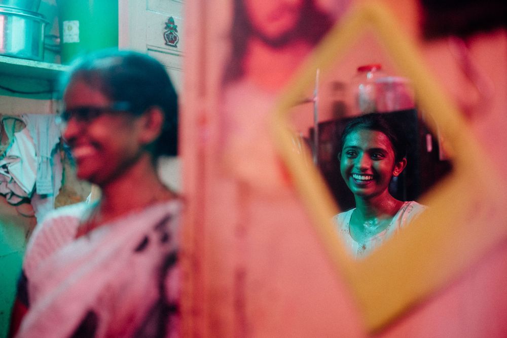 Creative portrait through yellow geometric frame with vibrant teal and pink lighting effects.