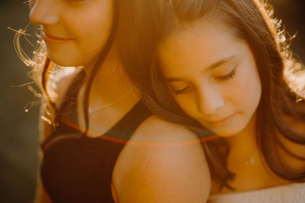Two figures in warm sunlight creating an intimate artistic portrait with soft focus and golden tones.