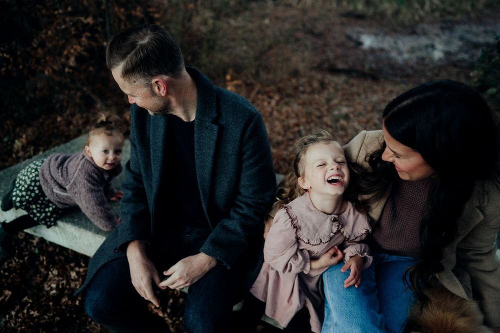 A family sharing laughs together during an autumn outdoor photo session.