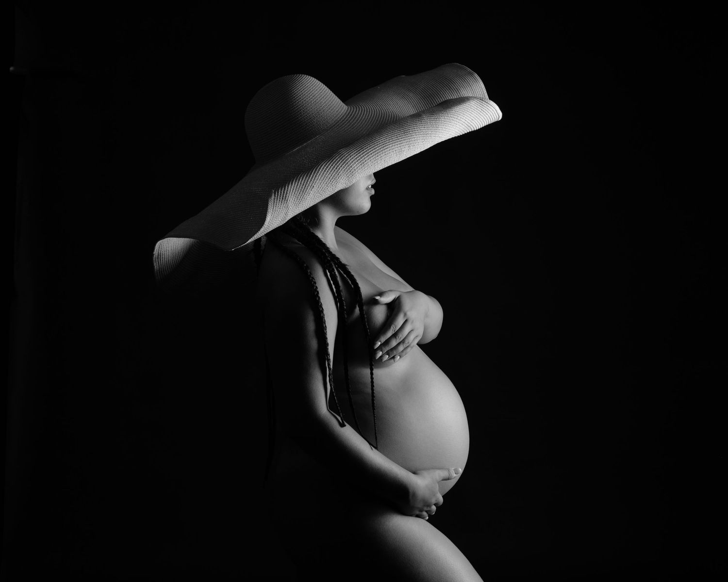 Artistic black and white maternity silhouettes in studio lighting.