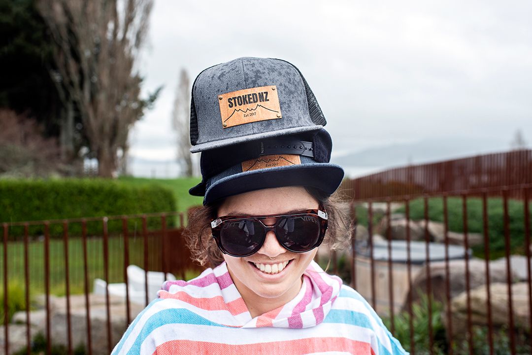 Portrait of a young women wearing sunglasses and several baseball caps, she's laughing
