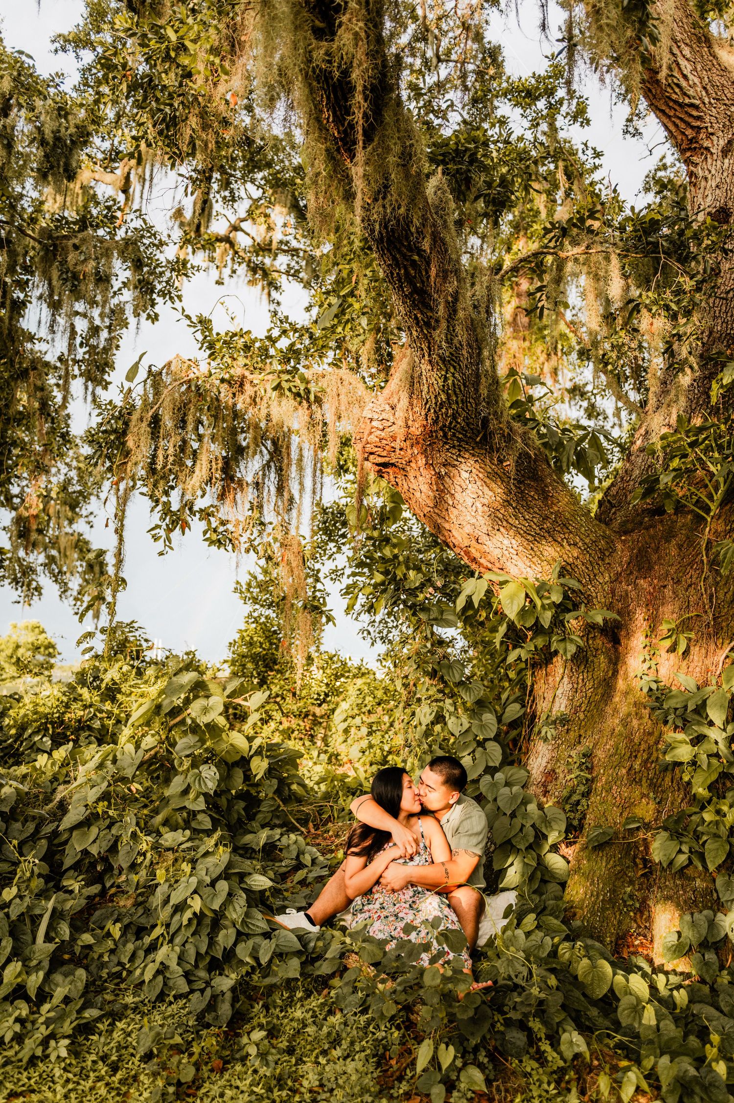 A person relaxes in a hammock under moss-draped oak trees at sunset, creating a serene outdoor scene.