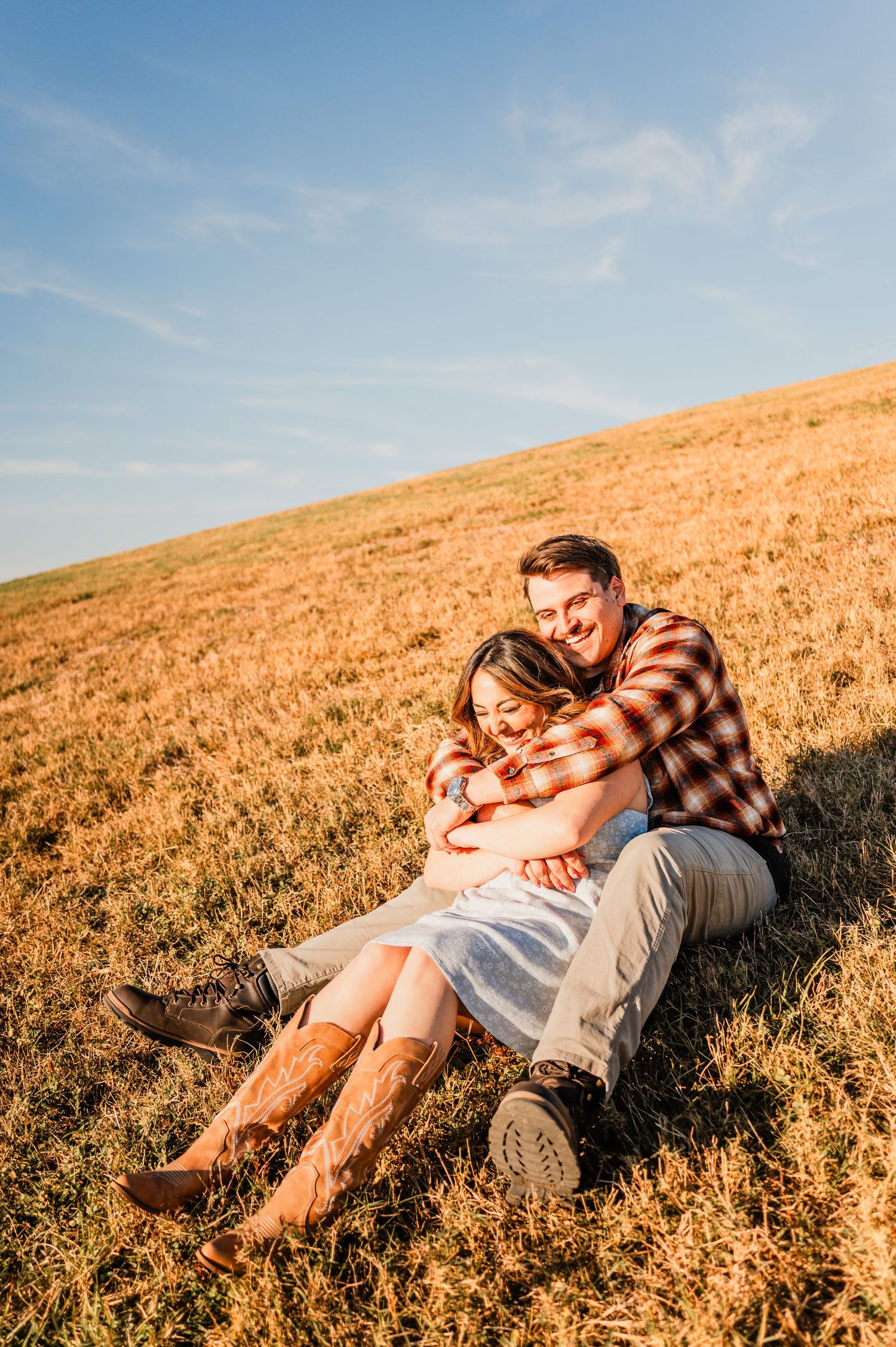 Couple lying together in a golden wheat field at sunset sharing an intimate moment in nature.
