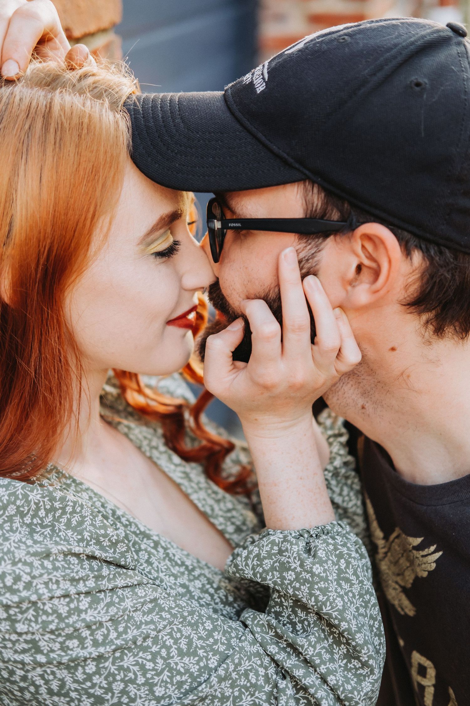 A tender moment captured between two people in a close embrace, with one wearing a black baseball cap.