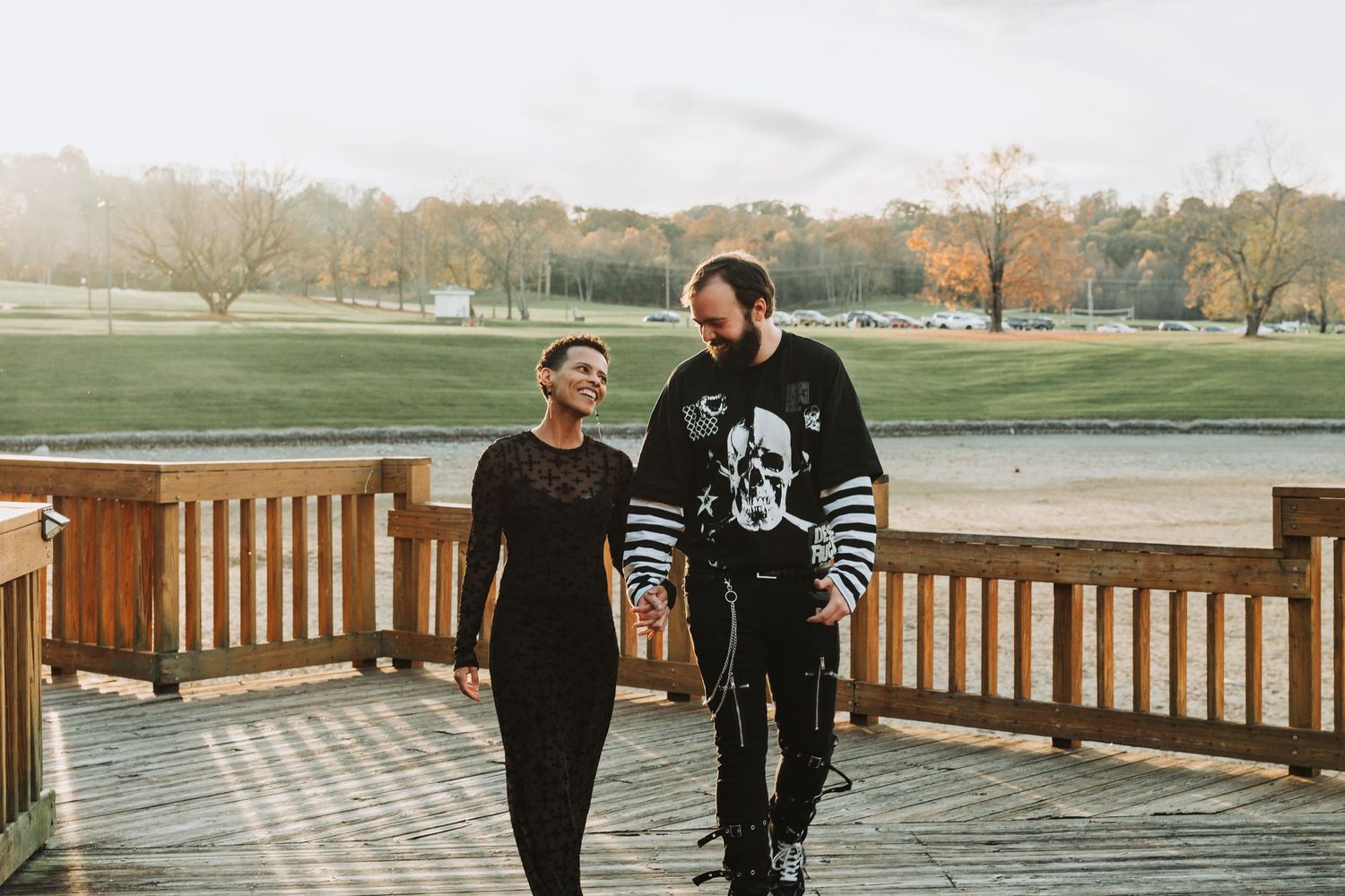 Two people walking together on a wooden deck overlooking an autumn field on a misty day.