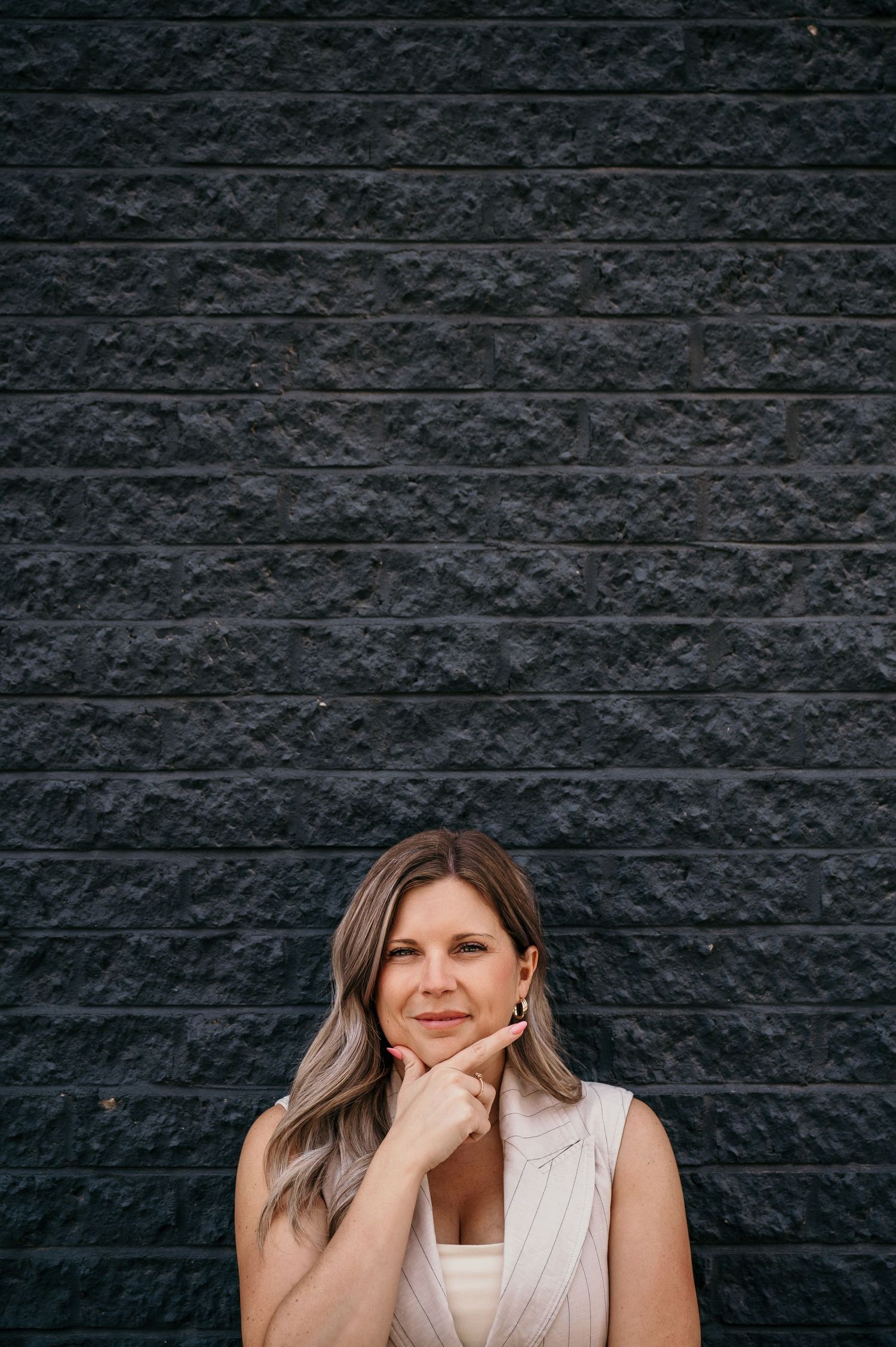 Candid portrait against black brick wall showing genuine laughter.