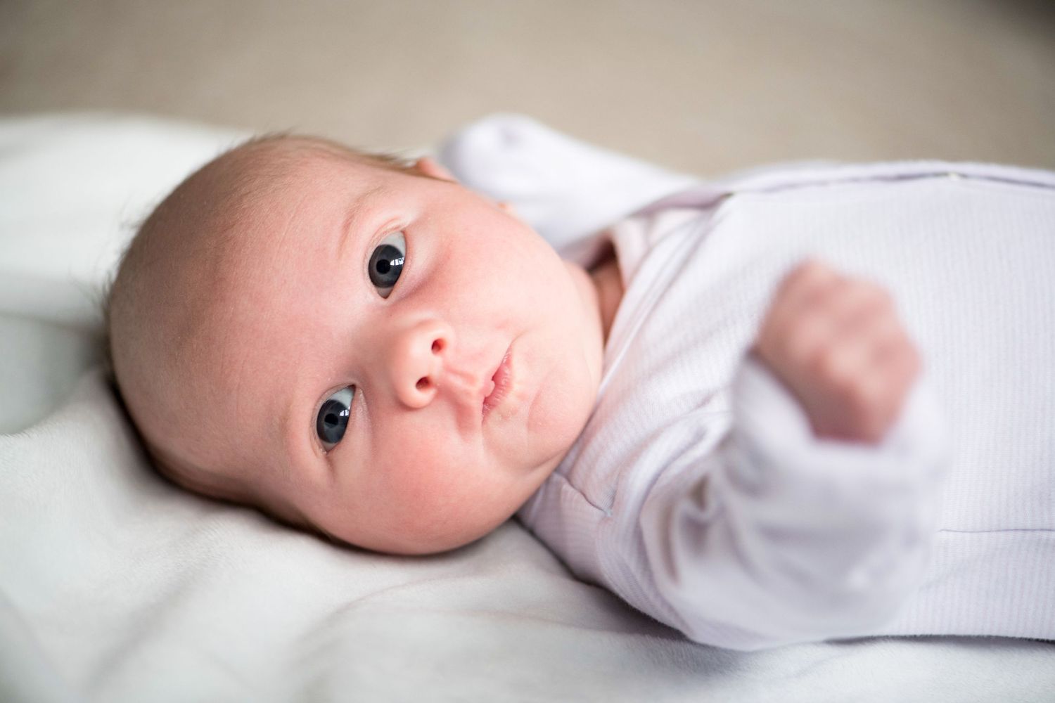 Newborn baby girl looking at the camera whilst having a stretch