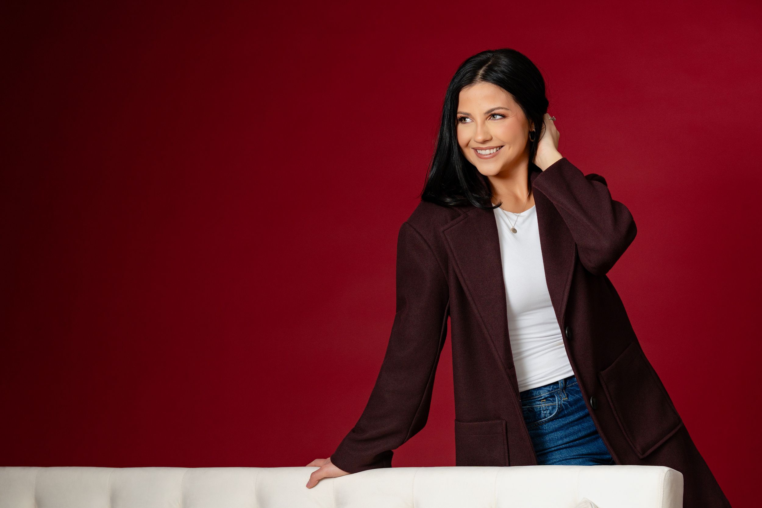Professional portrait of woman in burgundy blazer against red background. branding North Platte Nebraska Photographer