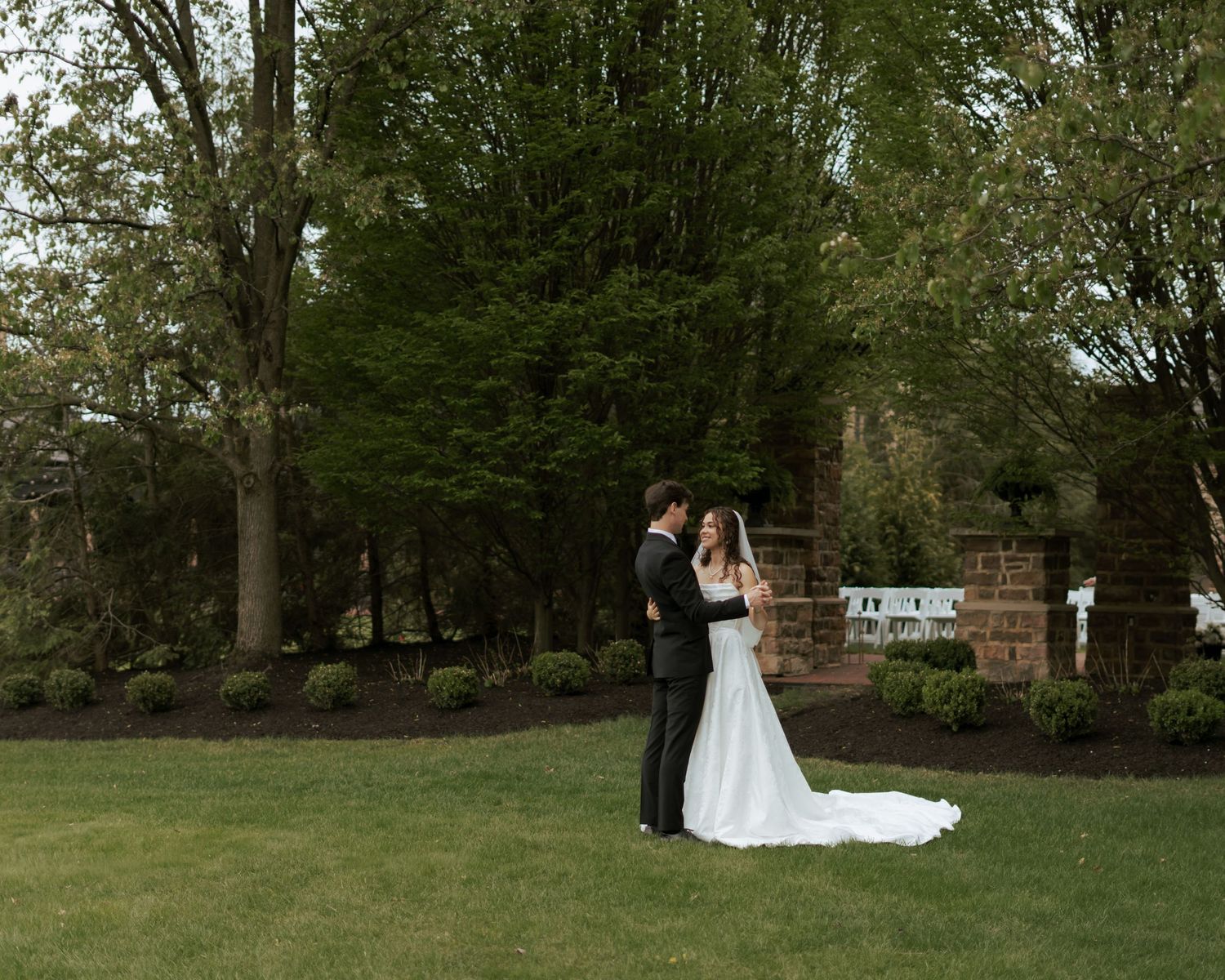 Picturesque bride and groom pose in magazine-like style in a vintage bell tower, looking away into the sunset. Gorgeous vintage wedding dres