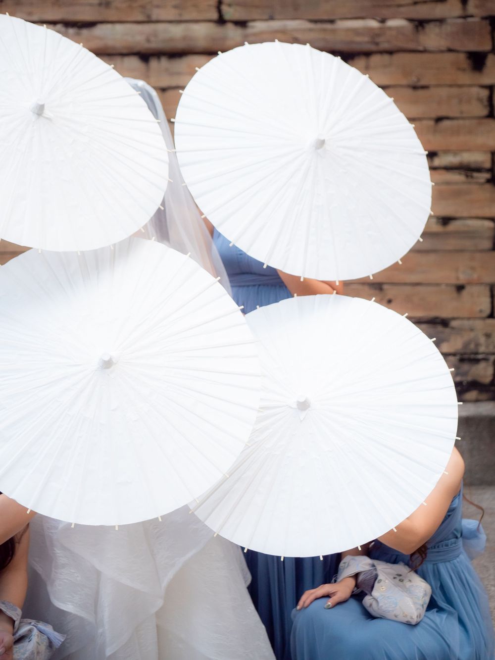 White paper parasols create an artistic composition against a brick wall backdrop.