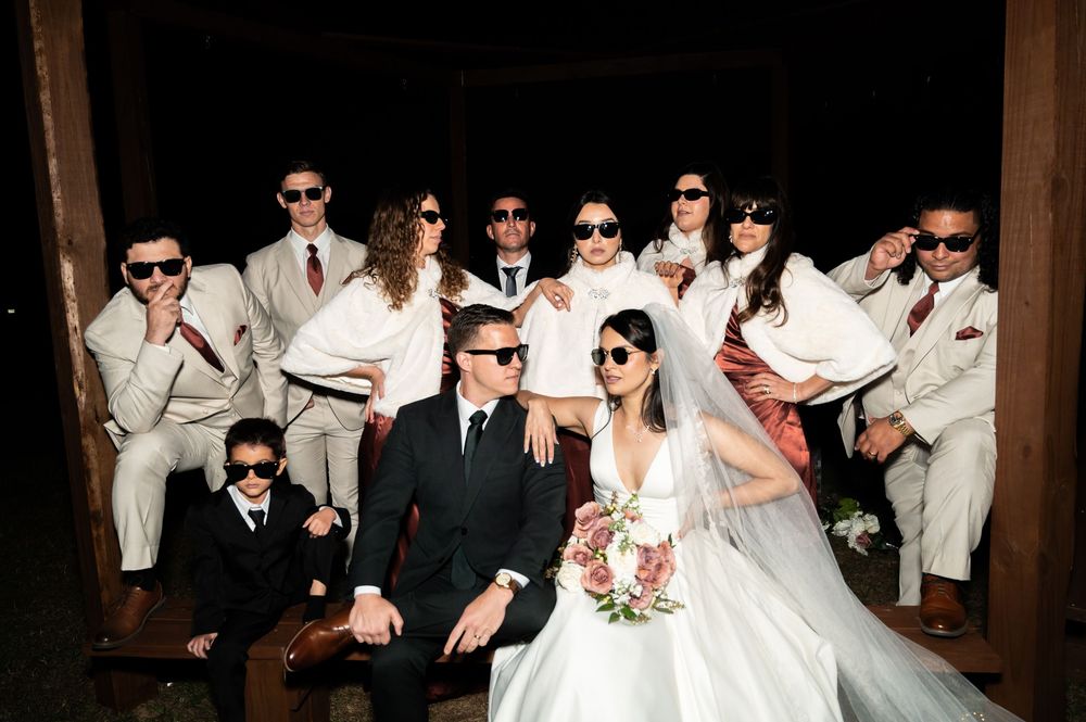 Wedding party wearing sunglasses posing together for a fun group photo.