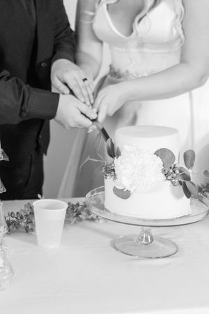 Black and white images show a couple cutting and serving a wedding cake in progressive stages at their reception.
