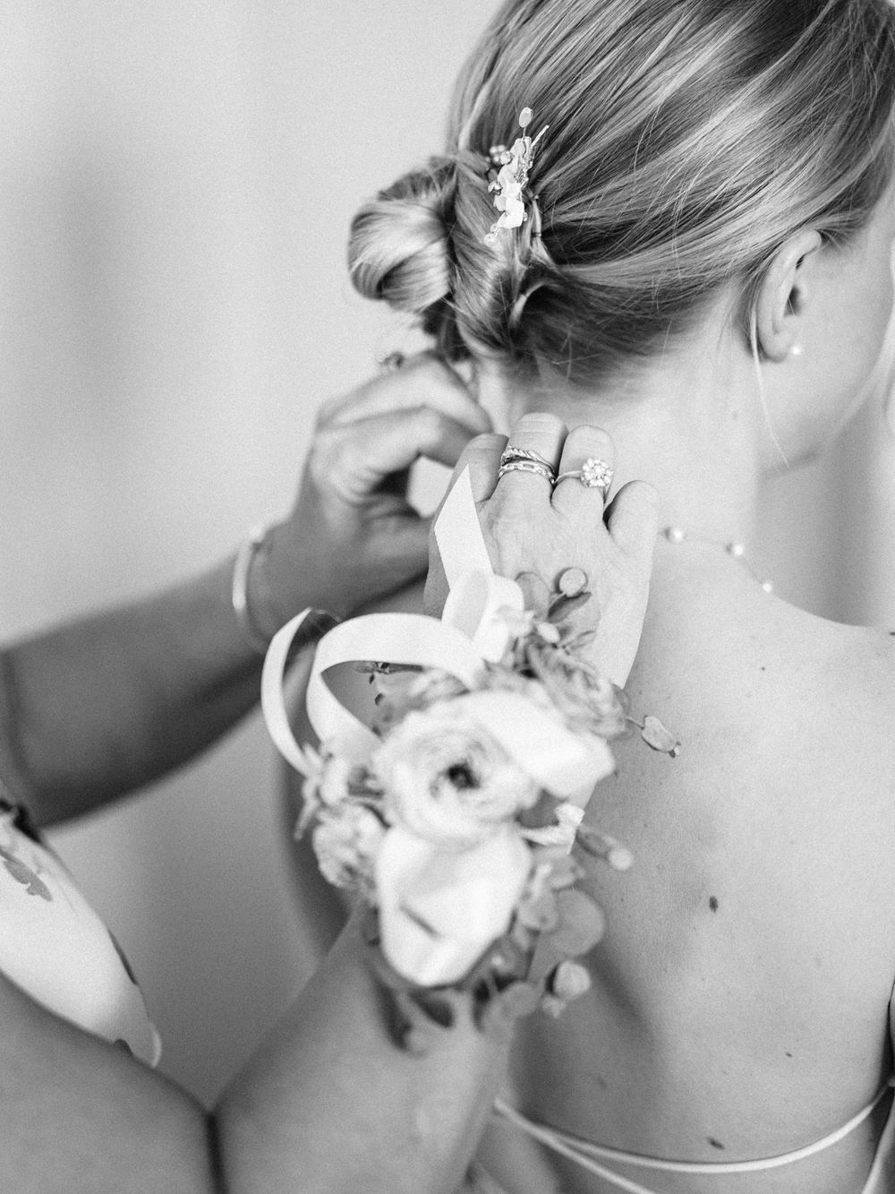 Close-up of a bride's elegant updo with floral hair accessories being styled.
