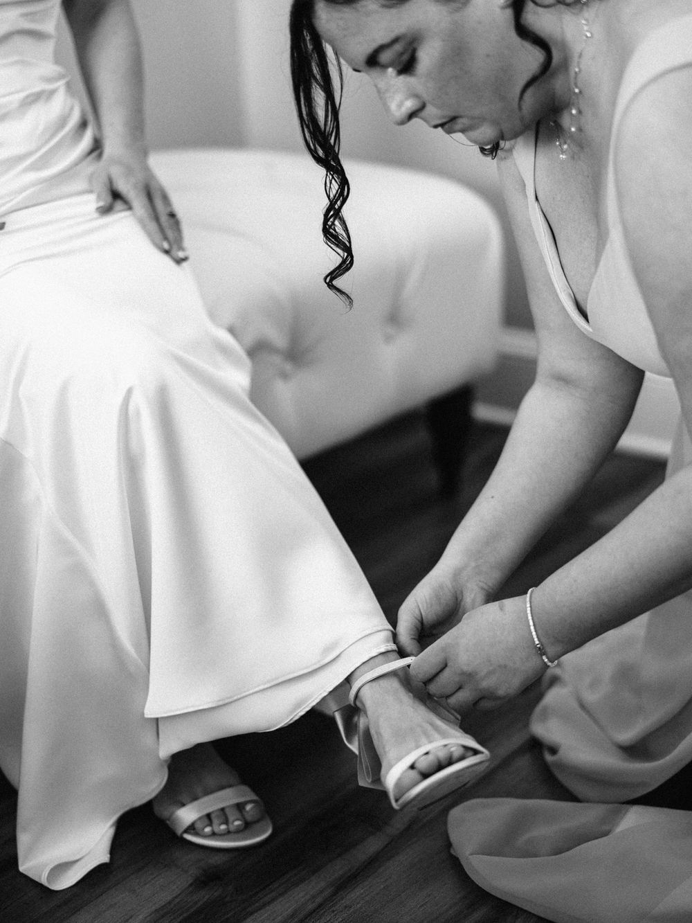 Close-up of someone helping adjust a white wedding shoe.