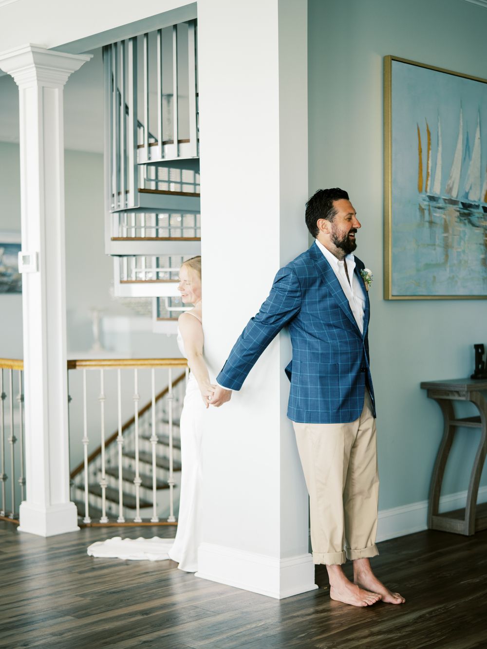 First look wedding moment with couple separated by wall in coastal-themed interior.