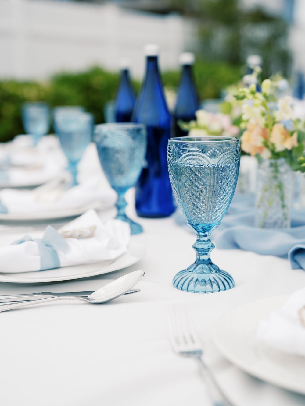 Blue vintage glassware and place settings on white tablecloth with navy blue accents.