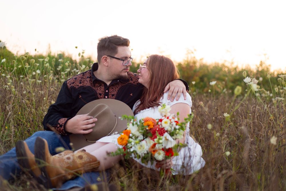 Romantic couple's outdoor engagement photo session featuring vibrant wildflowers and autumn sunlight.