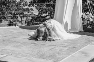 Black and white photo of a bride kneeling on outdoor dance floor at wedding ceremony.