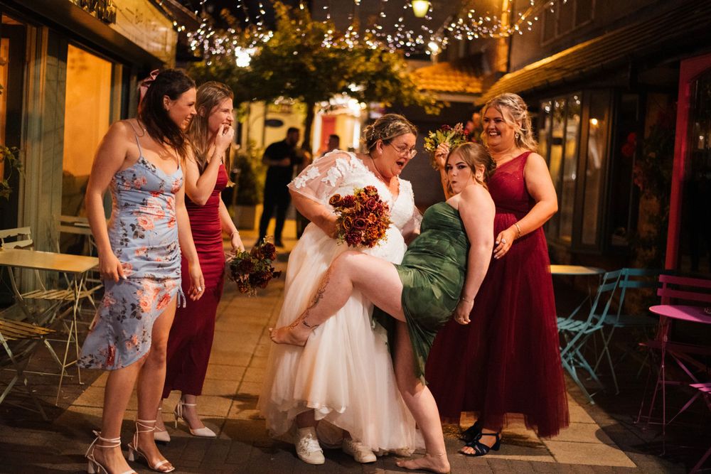 Wedding party celebrates on an outdoor patio illuminated by string lights.