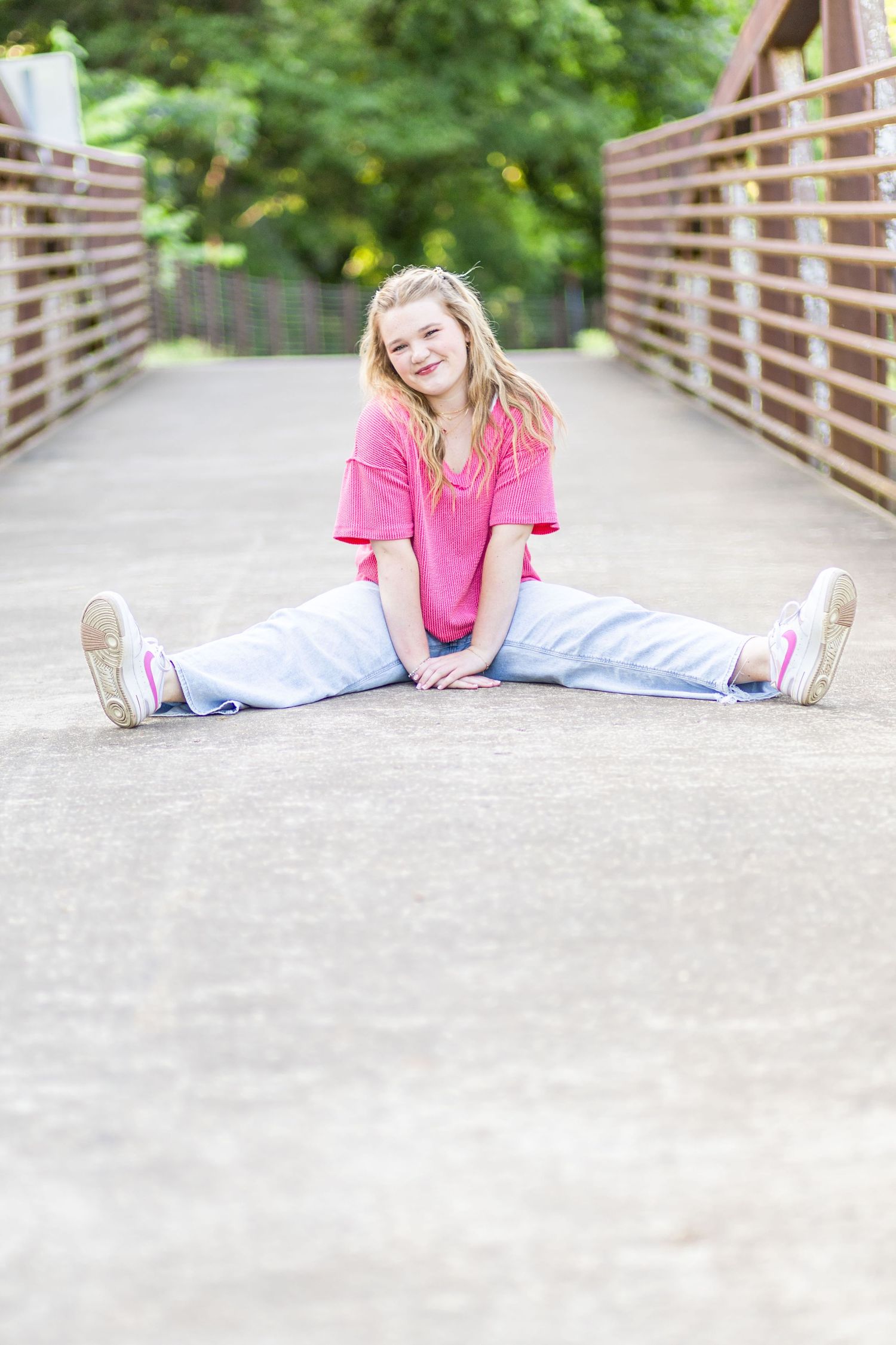 High school senior sitting on bridge looking at camera.