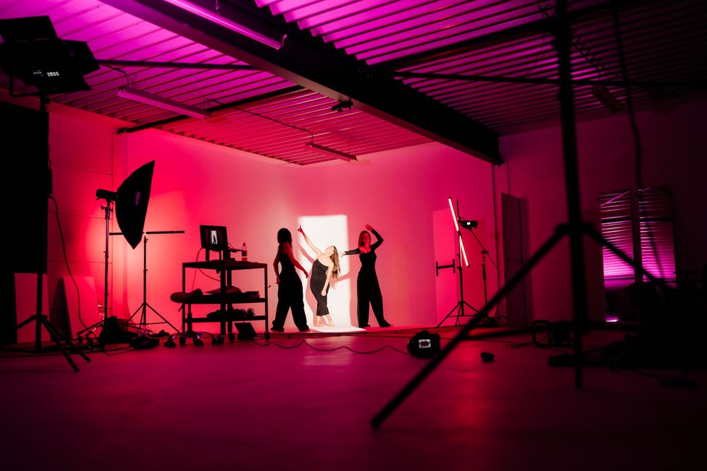 Empty photo studio with dramatic pink lighting and silhouetted equipment.
