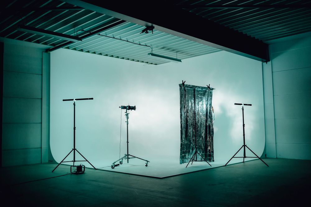 Professional photography studio setup with lighting equipment in cool teal tones.