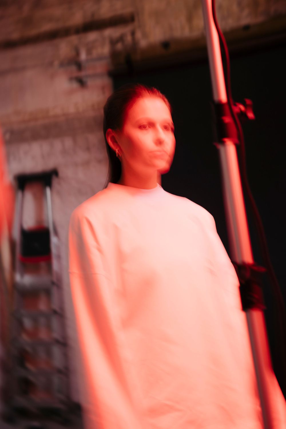 Figure bathed in red lighting creating an atmospheric silhouette against dark background.