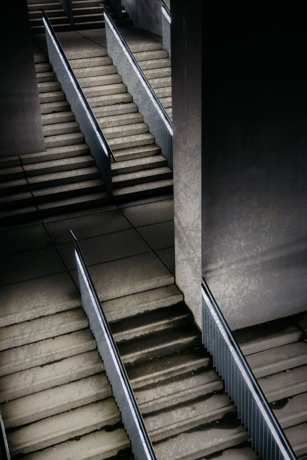 Modern staircase with metal handrails in dramatic lighting and shadows.
