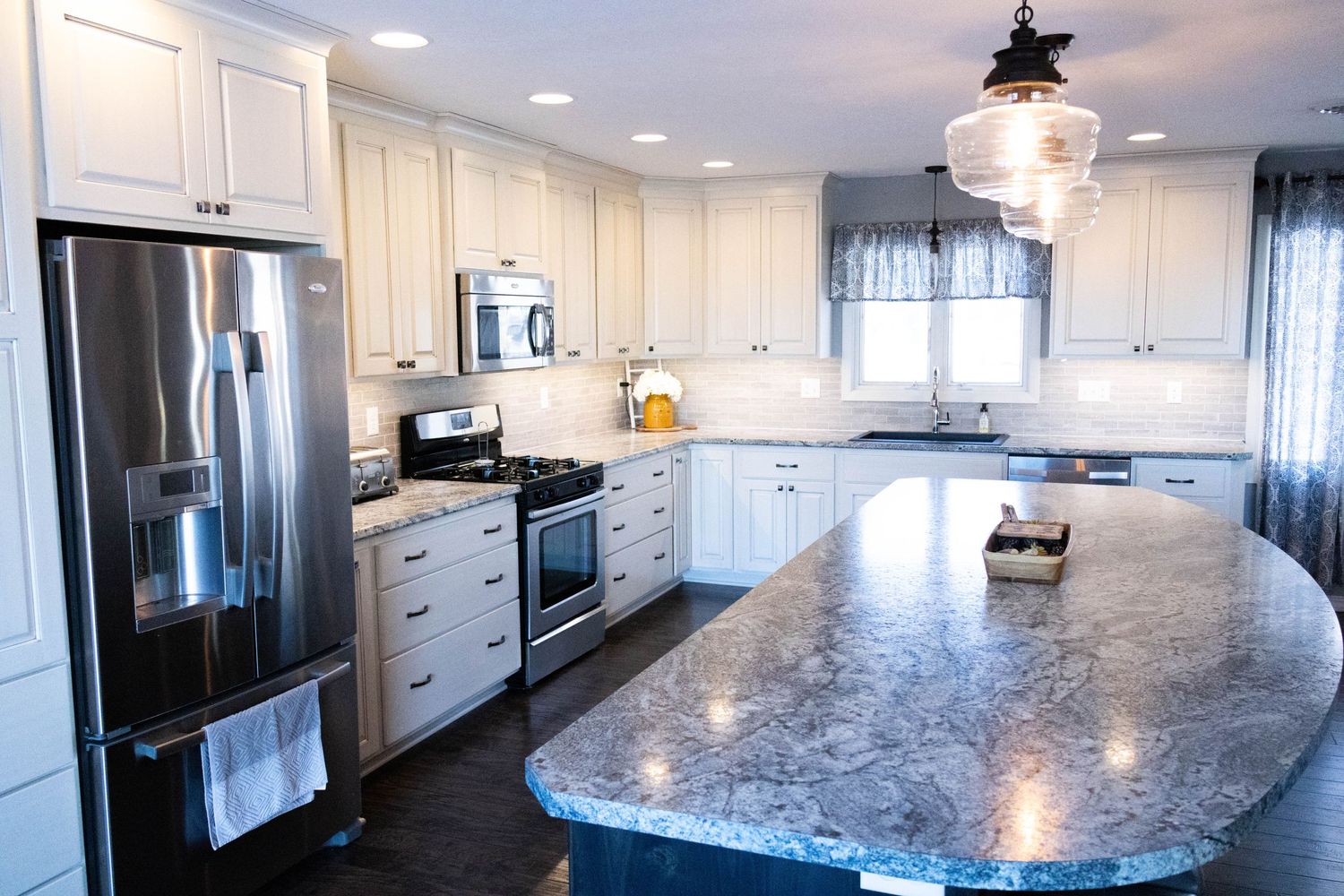 Spacious modern kitchen featuring white cabinets, granite countertops and stainless steel appliances.