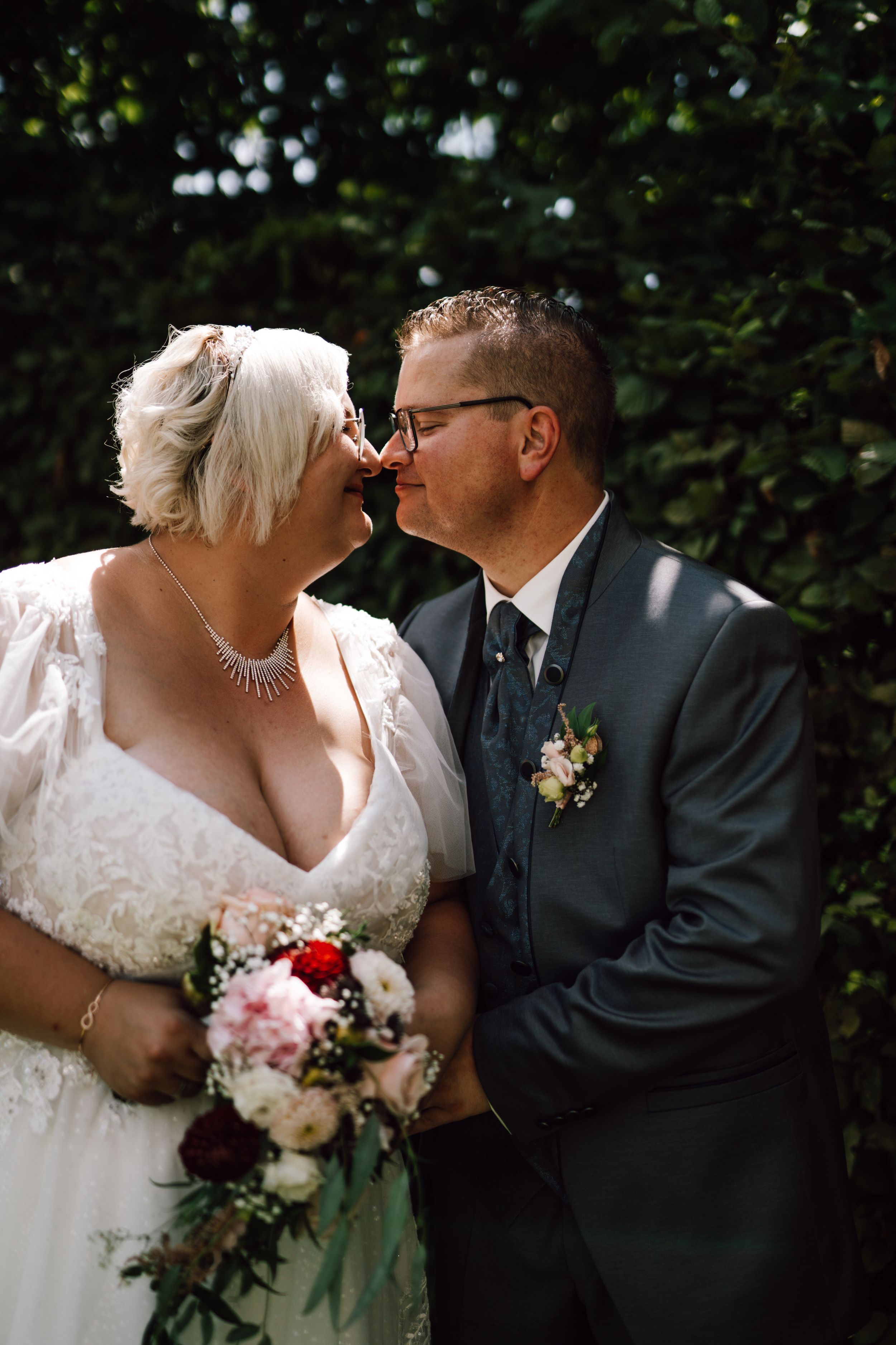 A romantic wedding moment captured in a garden setting with a bride in white and groom in black.