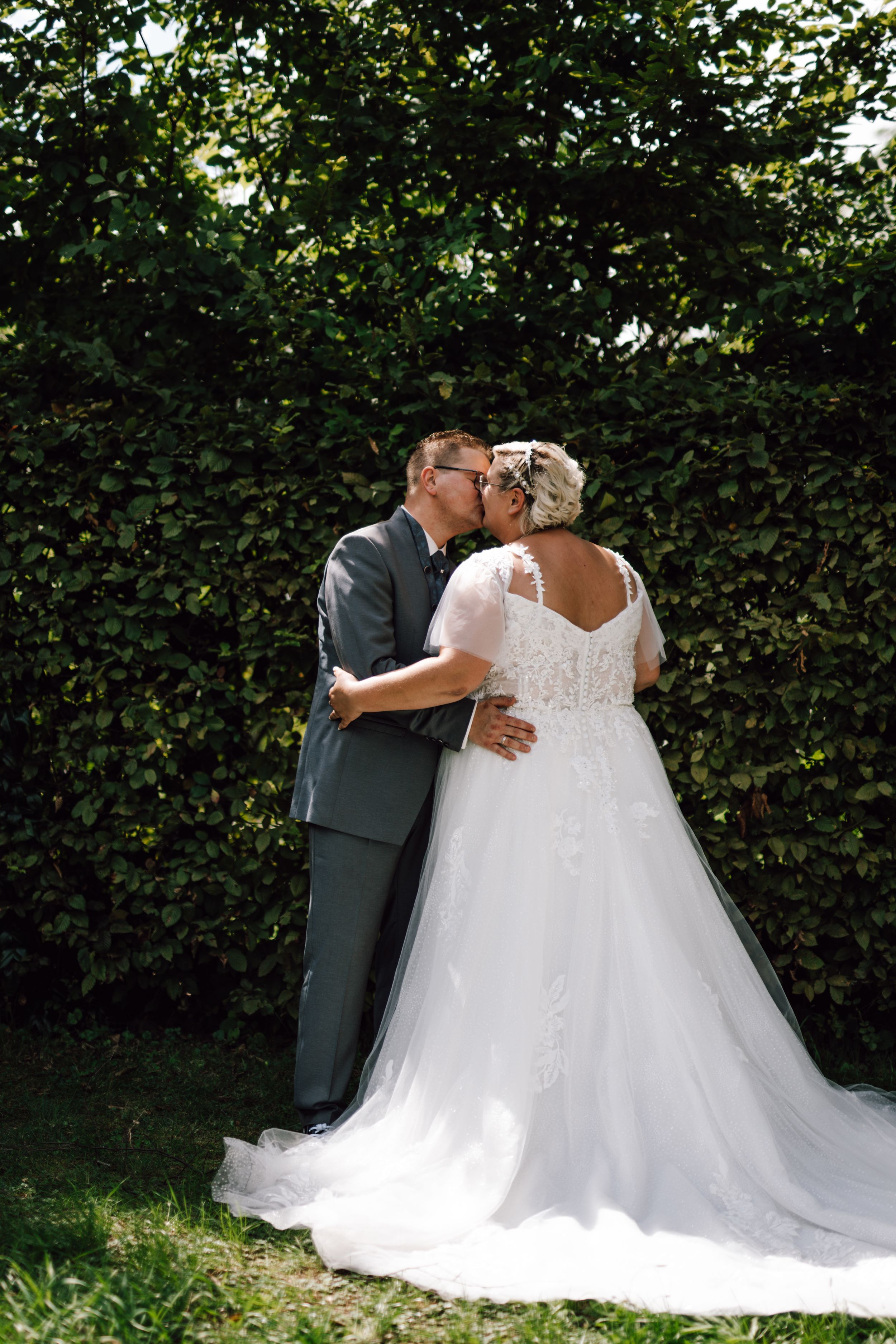 A tender wedding photoshoot in a lush garden setting with flowing white dress.