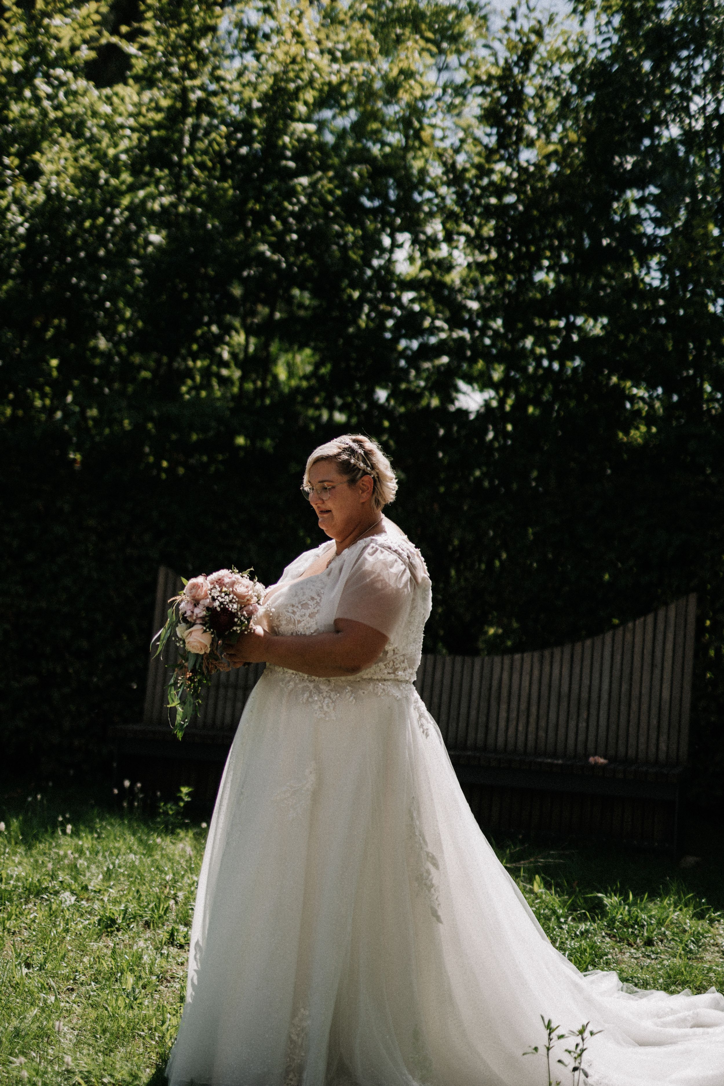 Beautiful wedding dress with flowing tulle skirt photographed in a sunny garden setting.
