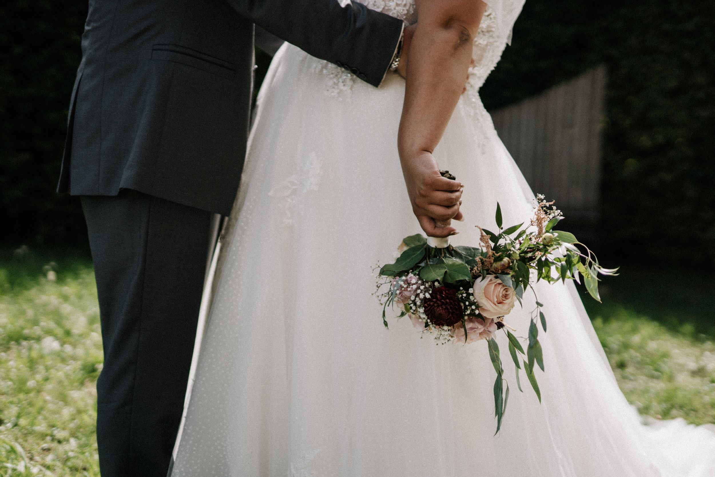Wedding couple photographed from waist down showing dress details and formal attire.