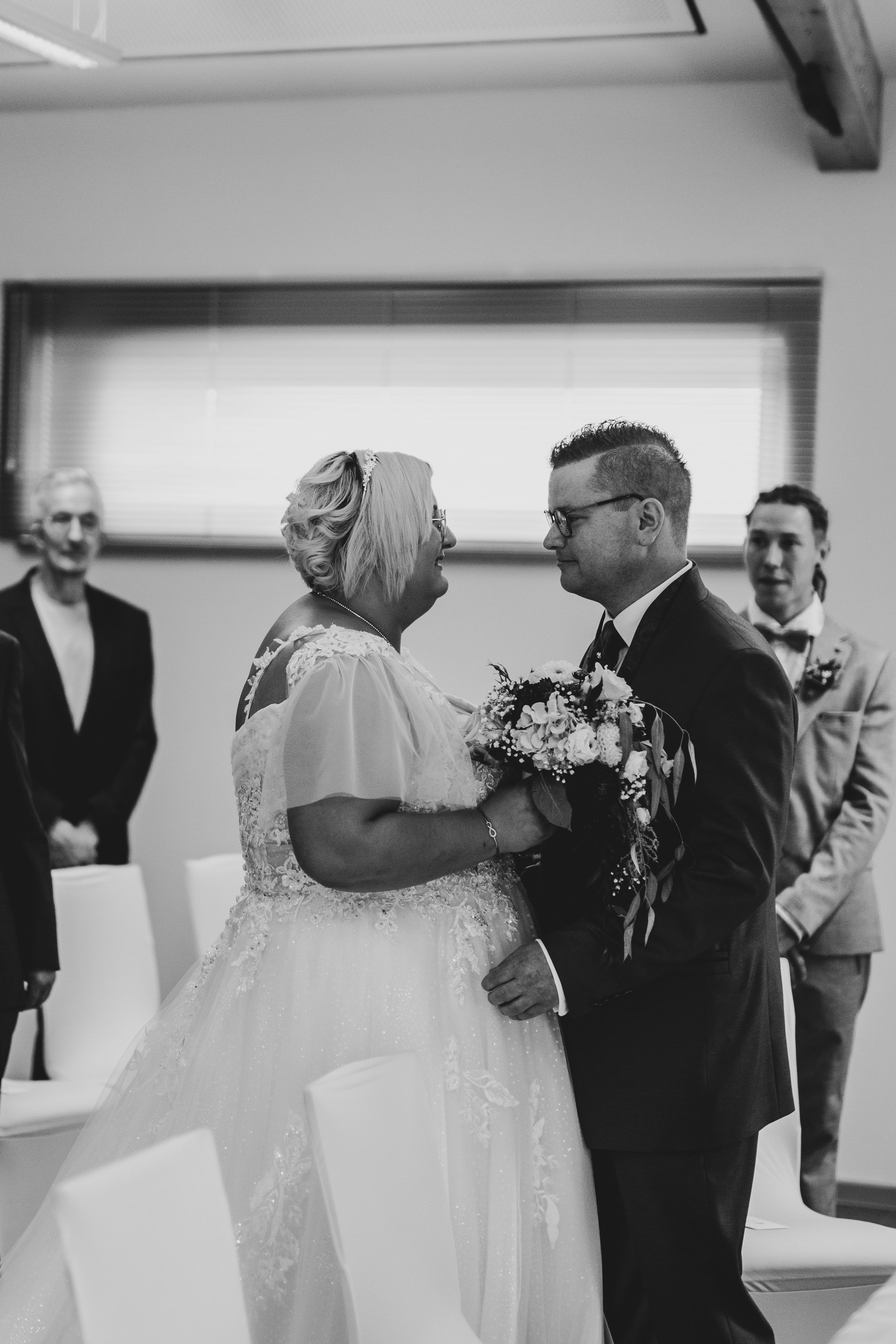 Black and white sequence of wedding ceremony moments in an indoor venue.