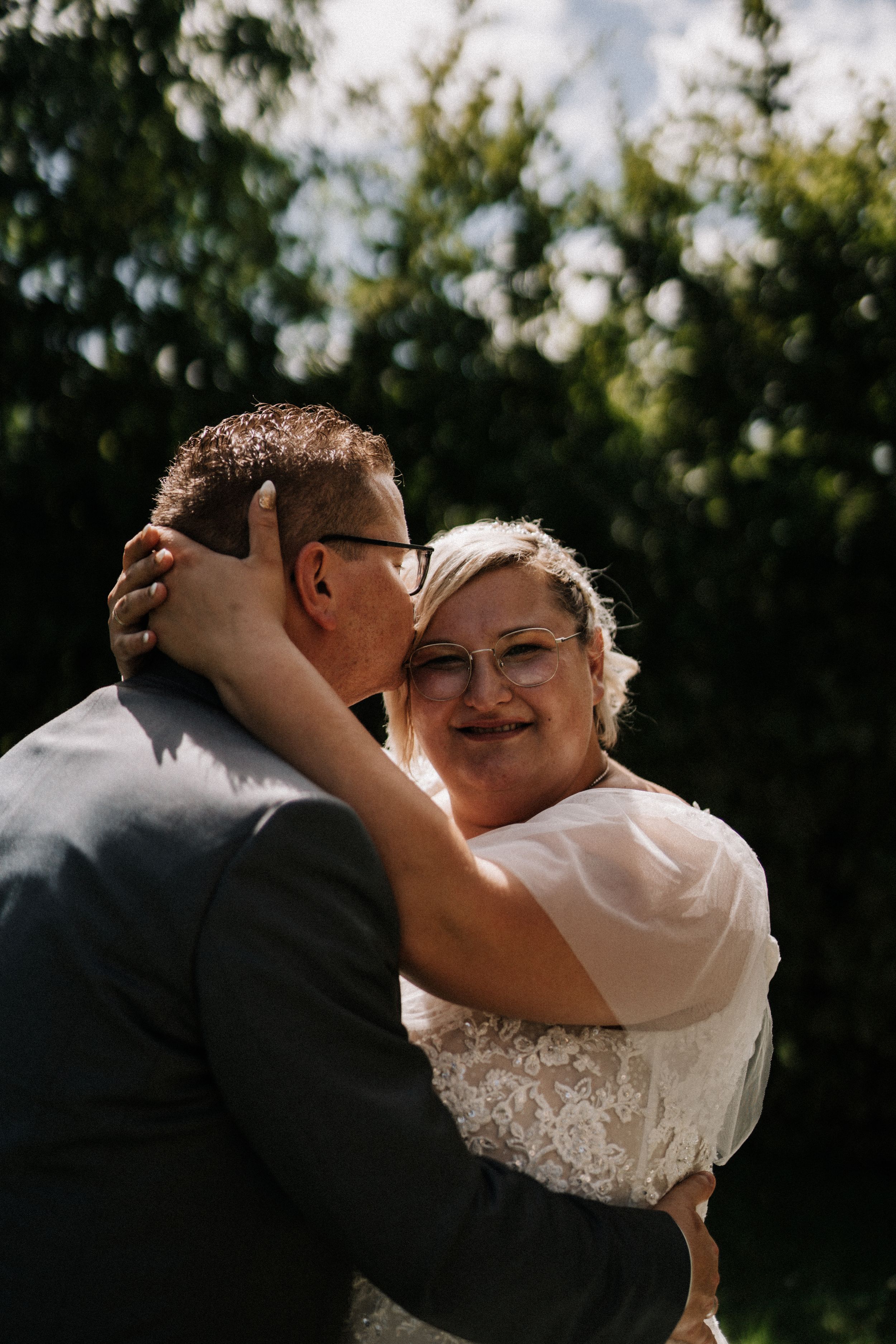 Joyful wedding embrace captured in natural outdoor lighting.