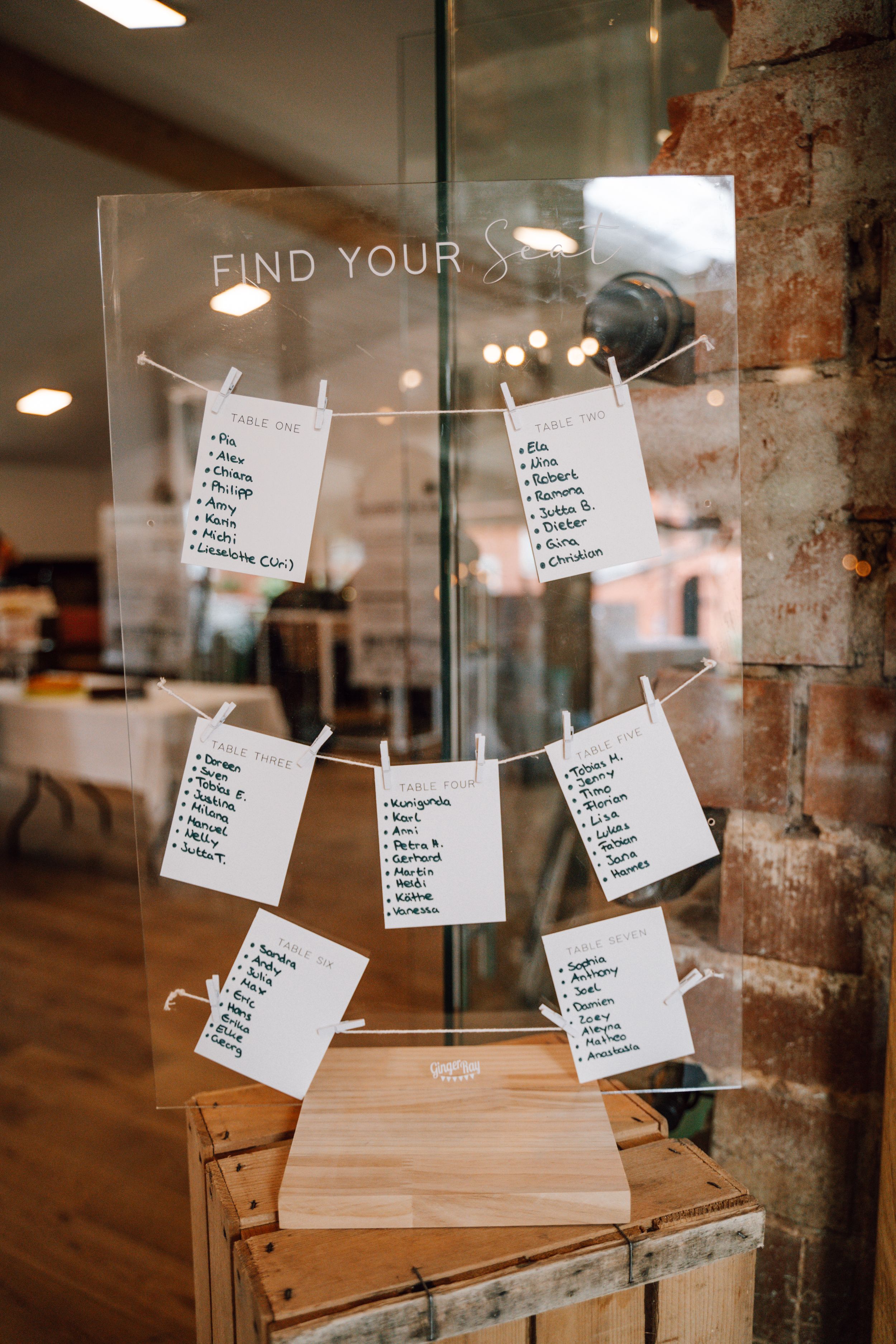 Wedding seating chart display with paper cards arranged on glass.