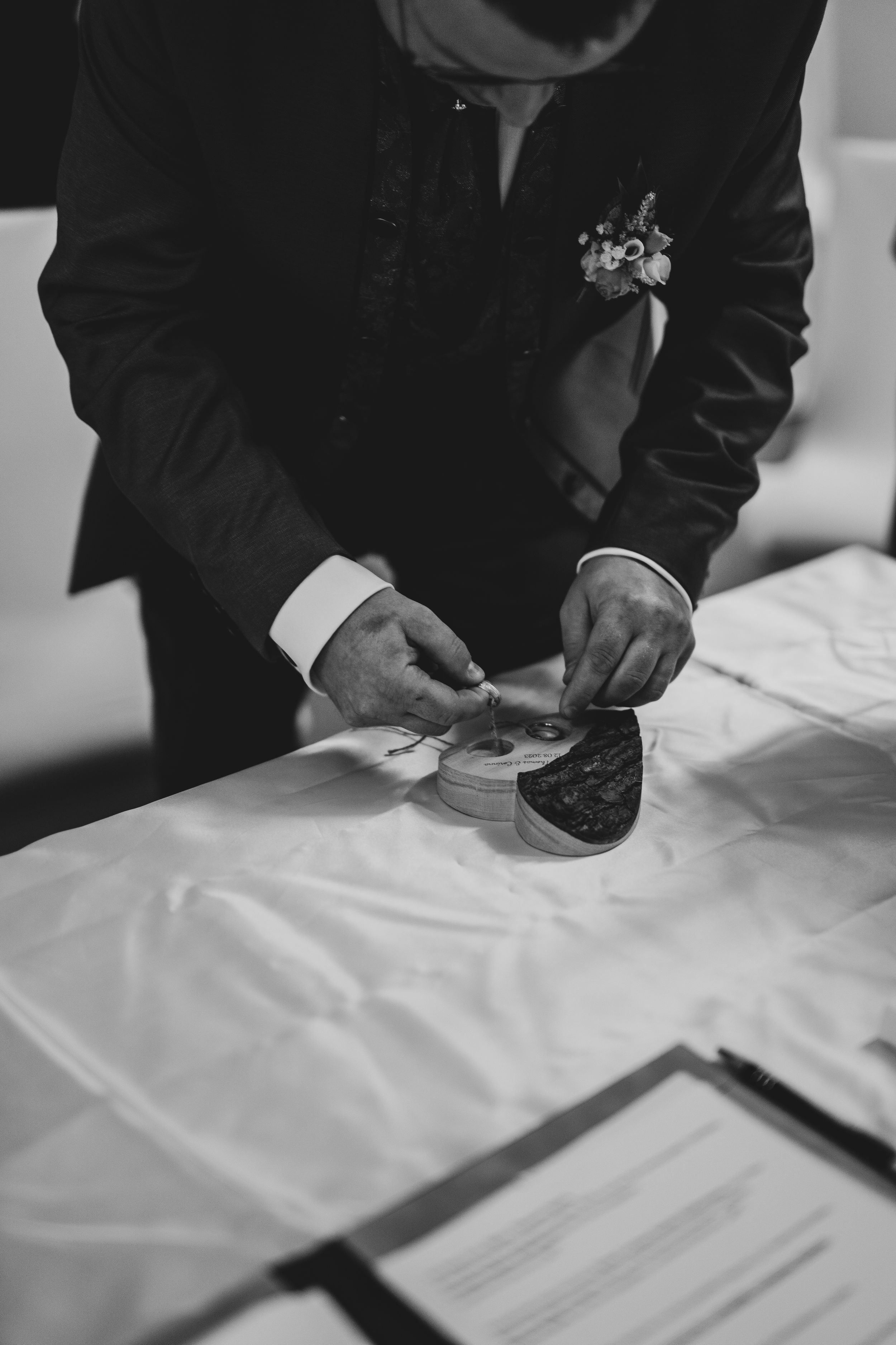 Close up of hands signing marriage documents in black and white.
