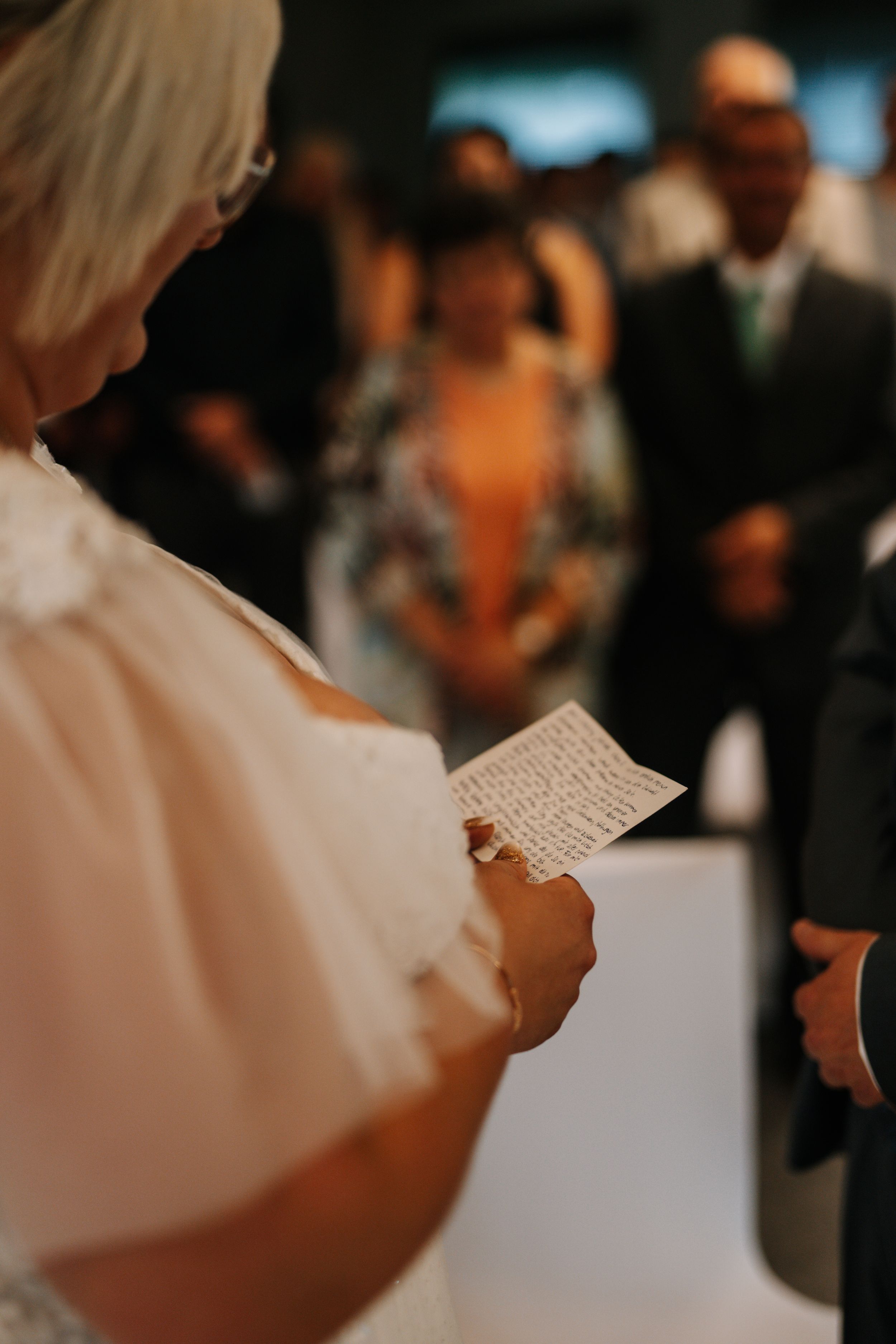 Bride reading vows from paper during wedding ceremony.