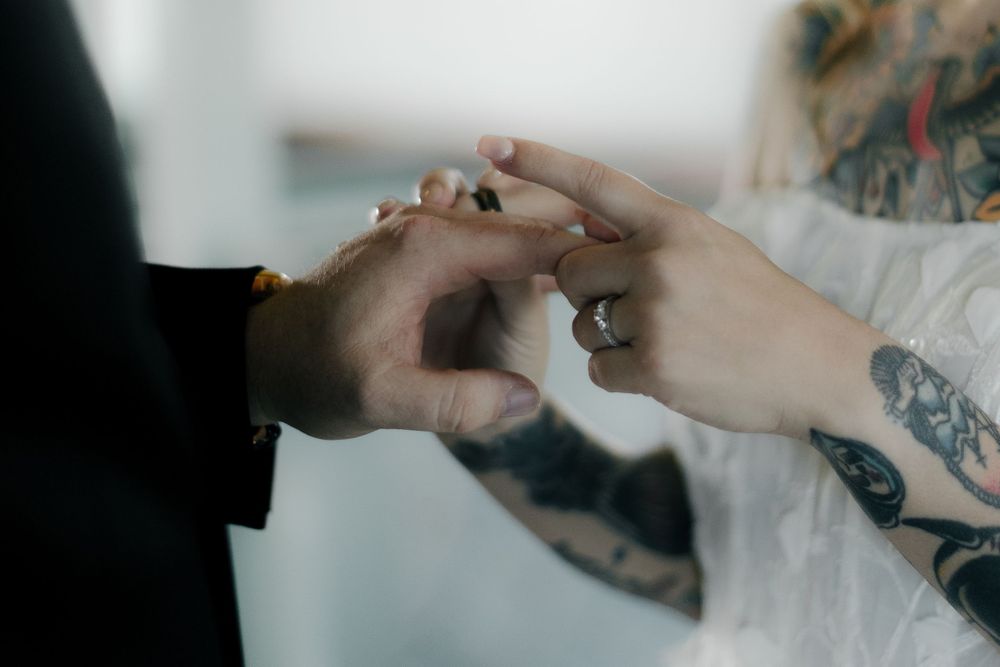Close-up shot of hands exchanging wedding rings during an intimate ceremony.