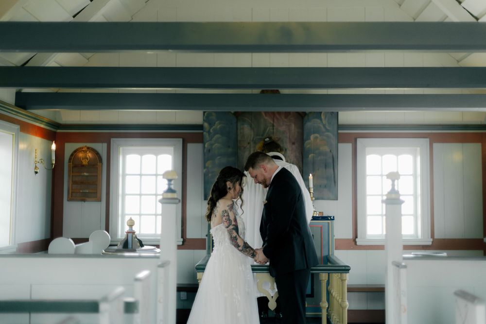 Interior of a rustic white church with wooden beams and windows.