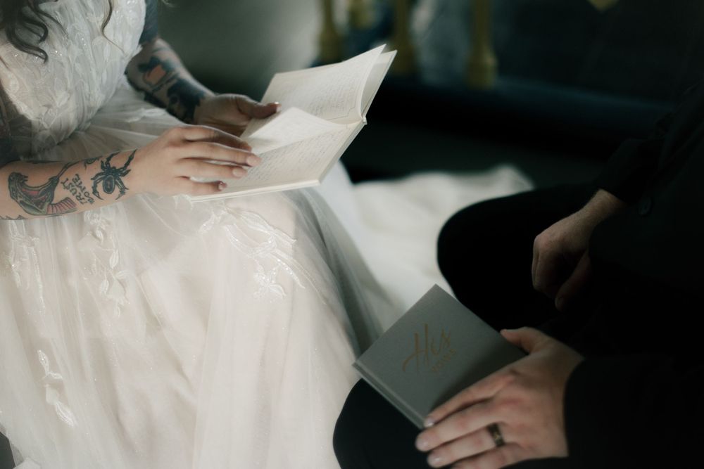 Detail shot of hands arranging white wedding dress fabric.