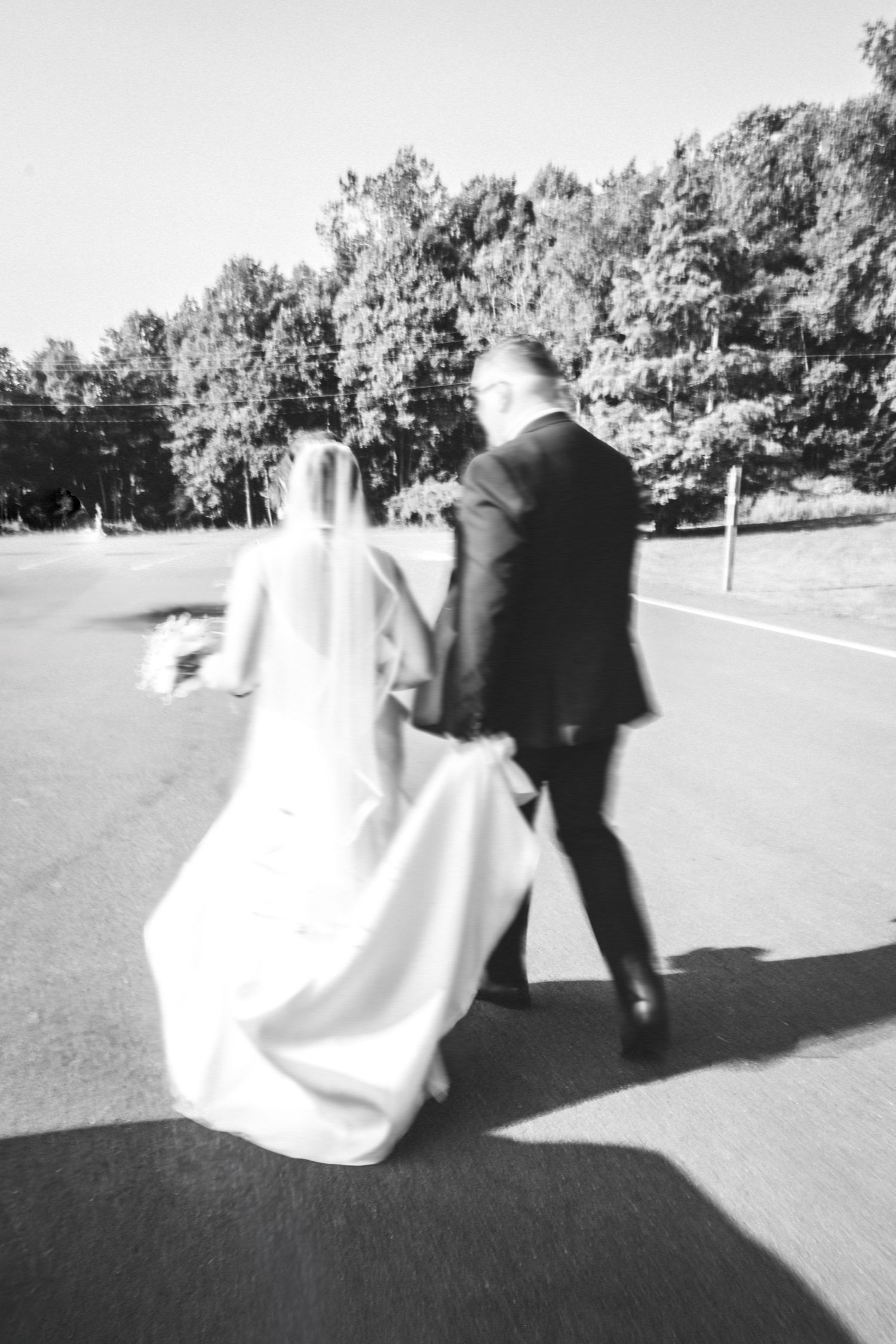 Blurred black and white photo of newlyweds walking together outdoors.