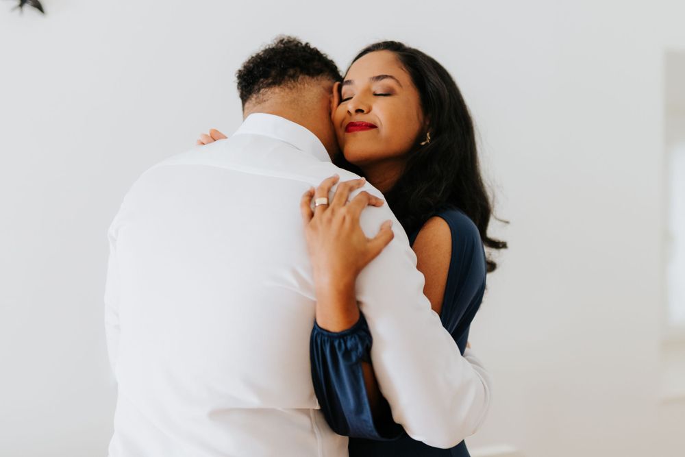 Couple sharing a tender embrace, woman in blue dress hugging man in white shirt.