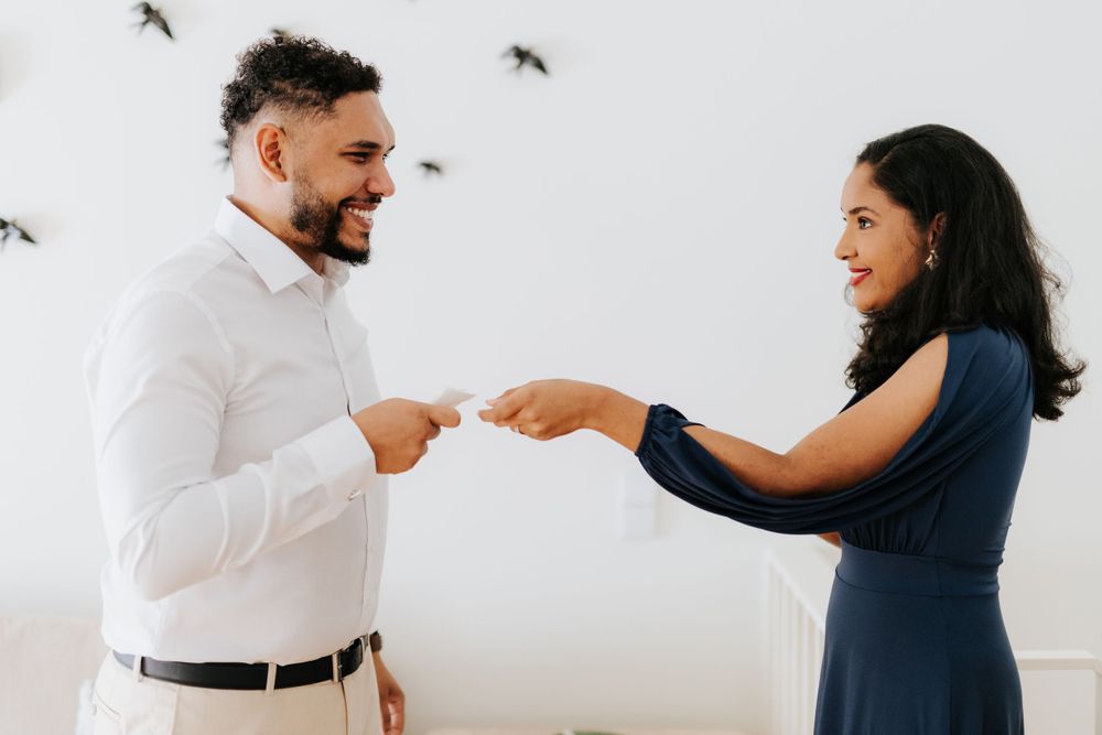 Smiling couple exchanging wedding vows cards in a bright white room with bird decor.